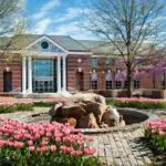 a building with a fountain and pink flowers