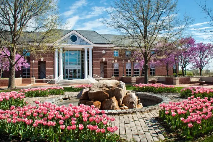 a building with a fountain and pink flowers